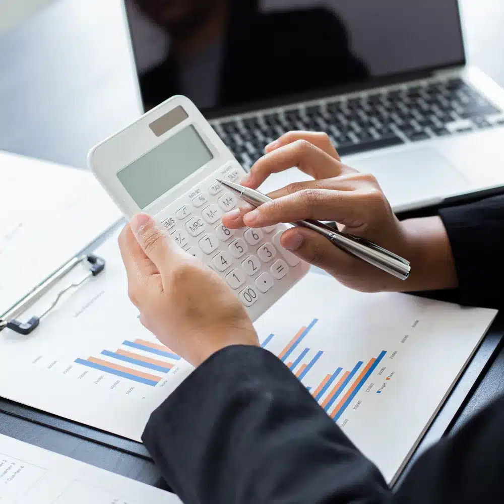 Business professional using a calculator and laptop to review financial records and accounting reports for cloud accounting in Toronto