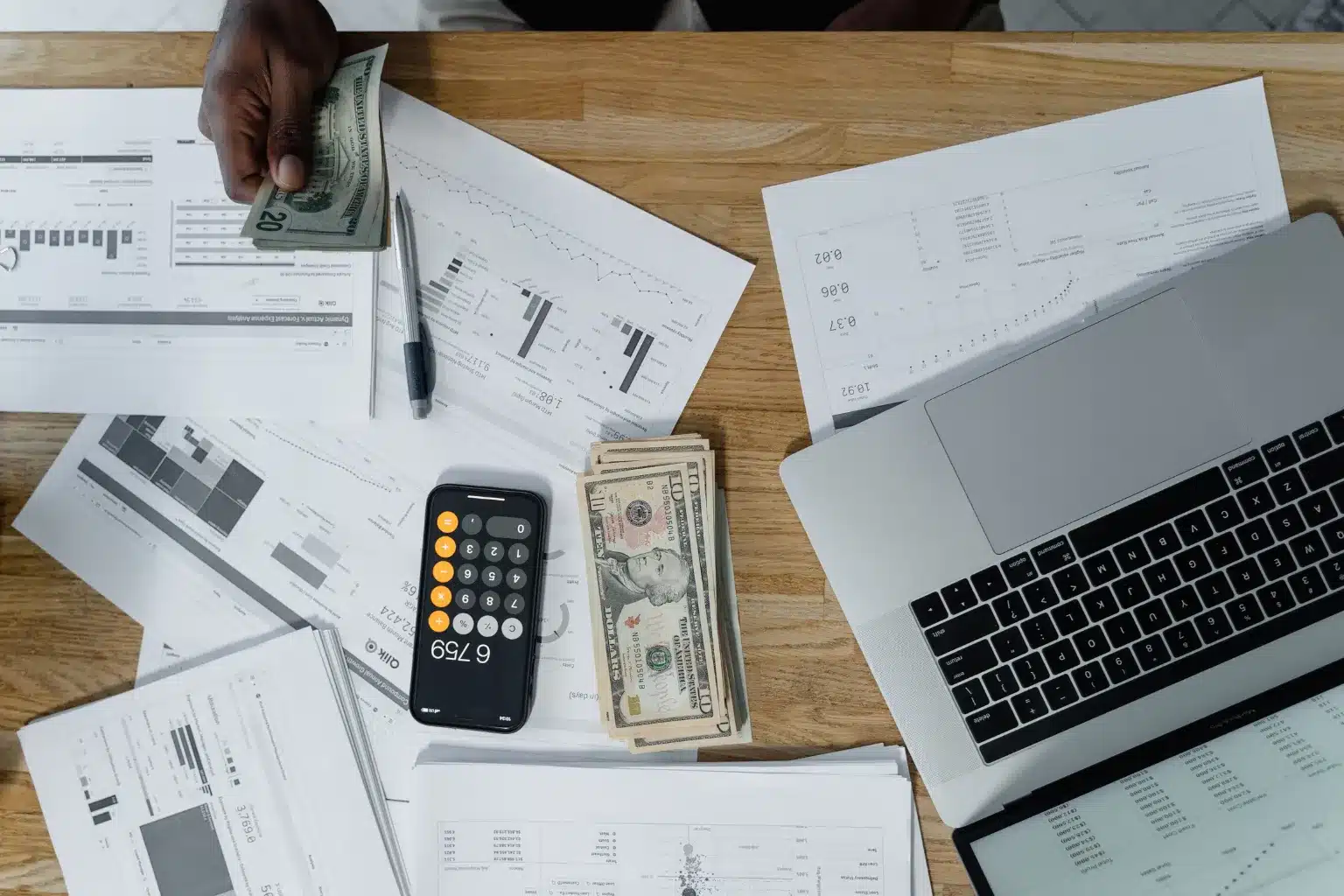 Payroll professional reviewing employee payroll records, deduction reports and year-end accounting documents in an office.